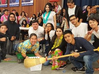 student group posing with broom and making hand signs