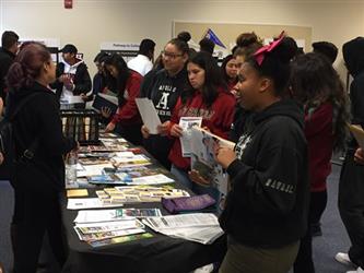 large group of students gathered around a table reading information sheets